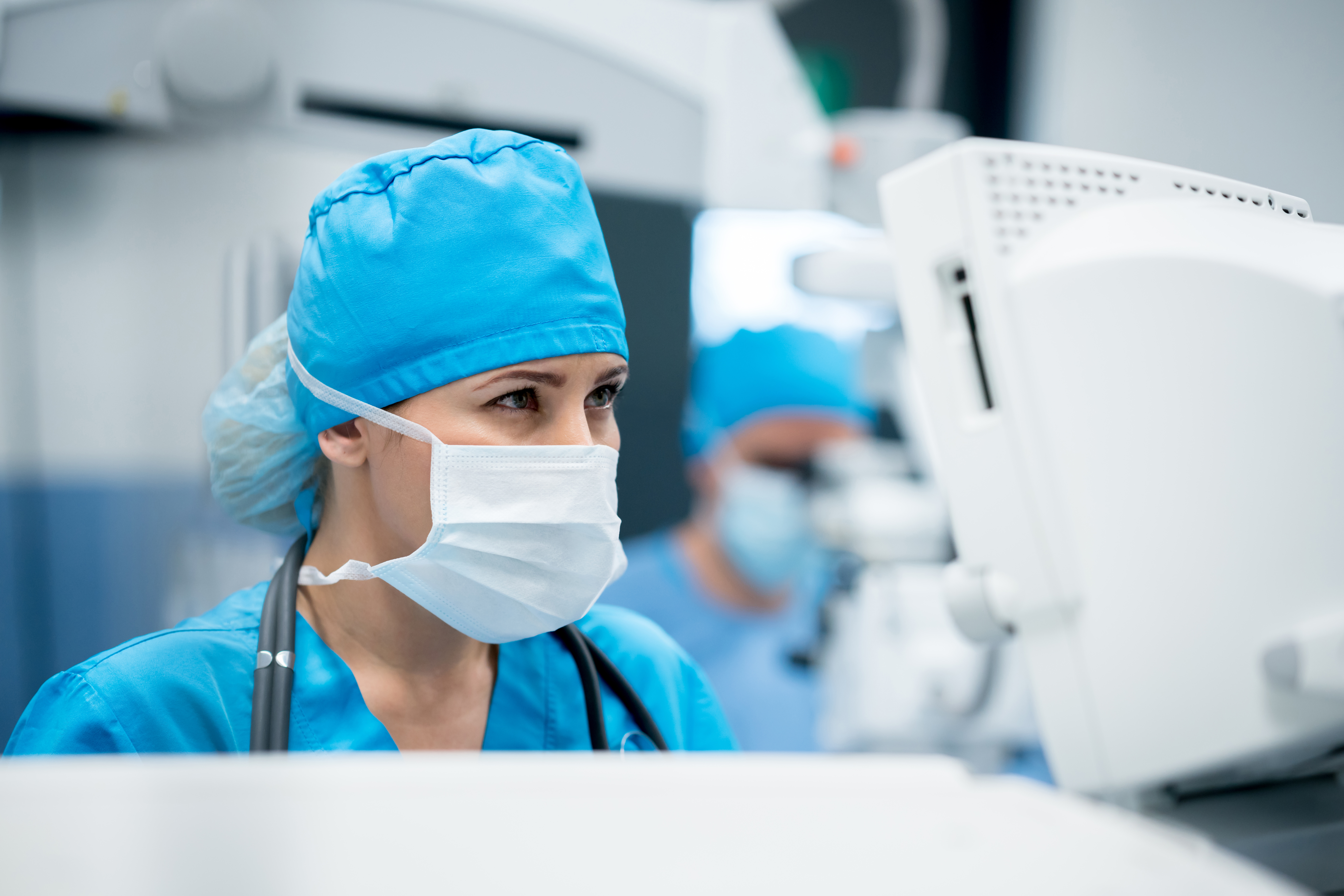 
  Surgeon standing in front of a computer dressed in surgical gear
