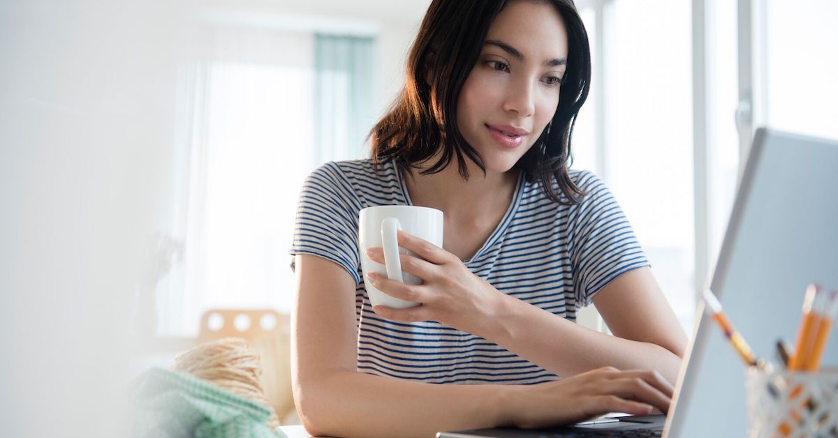 
  Person sitting at a computer while holding a cup of coffee
