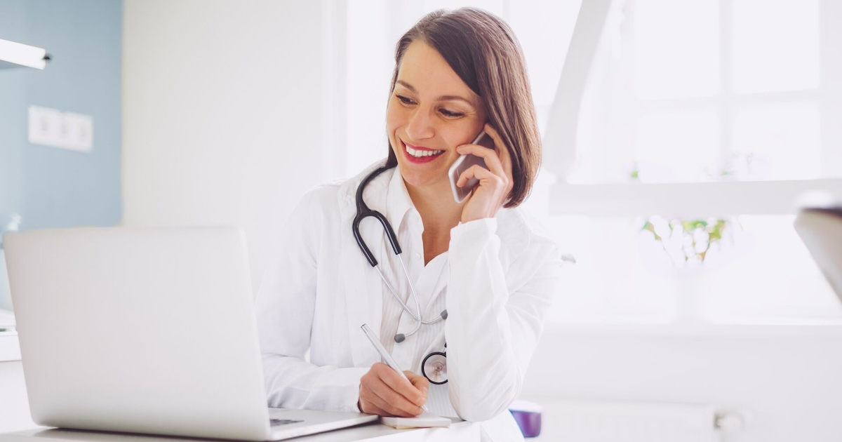 
  A doctor on the phone while checking a patient's record on a laptop computer 
