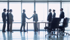 
  Two people shaking hands with six others watch
