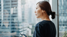 A person holding a smart phone looking out the window