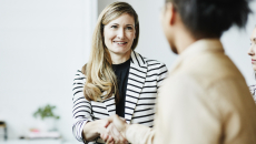 Two people sitting across from each other and shaking hands