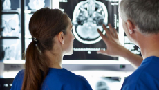 Two healthcare providers looking at a diagnostic image of a brain
