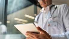 Healthcare provider standing up and looking at a tablet