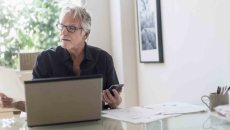 Person sitting in their home office while looking at a computer and a piece of paper
