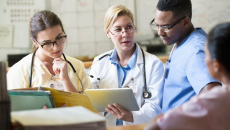 Healthcare providers sitting in a room and looking at a tablet
