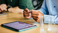 People sitting at a table with a tablet on it that has graphs on its screen
