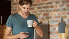 Cellphone user holding a cup of coffee while walking around