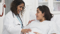 Pregnant person in a hospital bed with a doctor standing next to them