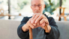 Person sitting down while holding a cane in front of them