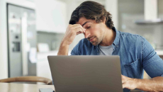 Stressed person sitting at a computer with their head in their hand