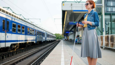 Blind person standing at a train station