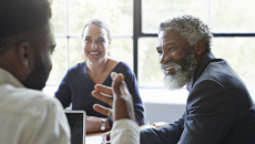 Three business people sitting around a table and talking