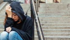 Person sitting on steps with their head in their hands