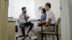 Doctor sitting in an exam room with two patients