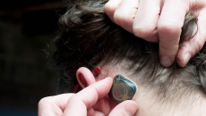 A person pulling back their hair to place the sensor