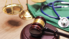 A gavel next to a scale and a stethoscope