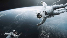 Two astronauts floating above earth in space reaching for each other
