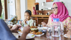 People sitting around a dining room table with food on it