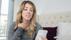 Person on a cellphone holding their throat