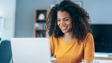 Person sitting at a computer looking at the screen while smiling