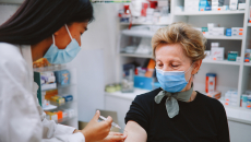 Person sitting in a pharmacy and getting an injection by a pharmacist