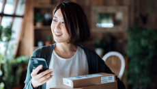 Person smiling while in their home and holding a phone with boxes around them