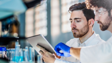 Two scientists in a laboratory looking at a tablet