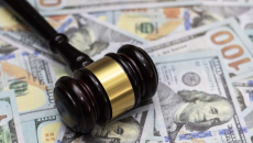 A gavel lying on a pile of $100 bills