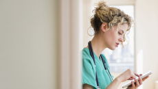 Healthcare professional standing in a hallway while looking at a tablet