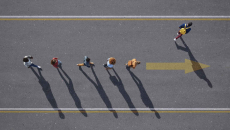 People walking in a line with one person walking elsewhere