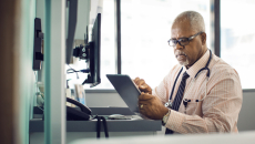 A doctor sitting at a desk using a tablet