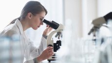 A researcher using a microscope in a lab