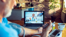 An older man talking to a provider via telehealth while checking his blood pressure