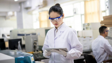 A researcher in a lab looking at a tablet