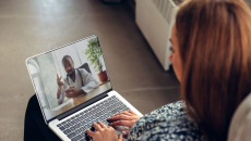 A person talks to a doctor though a video chat on her laptop.
