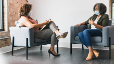 While wearing protective face coverings, a therapy patient and therapist discuss something.
