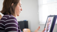 Person sitting at a computer speaking to a healthcare provider on the screen