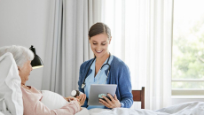 Healthcare provider in a patient's home sitting next to a patient lying in bed