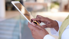 Person holding a tablet while wearing a white outfit with a yellow scarf