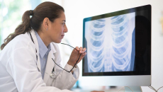 Healthcare provider sitting down and looking at a computer screen with diagnostic images on it