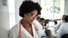 Healthcare provider standing in a hallway looking at a tablet