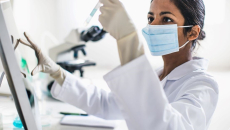 Person wearing mask holding test tube