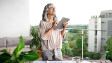 Person standing on a balcony with a tablet in their hand