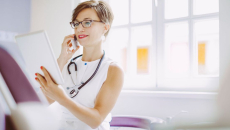 Healthcare provider looking at a tablet while talking on a phone