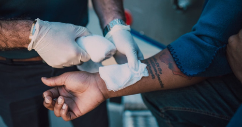 Patient with wounded wrist being patched up with bandage
