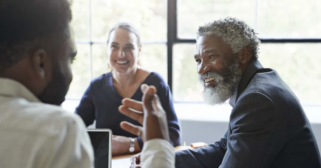 Three business people sitting around a table and talking
Three business people sitting around a table and talking