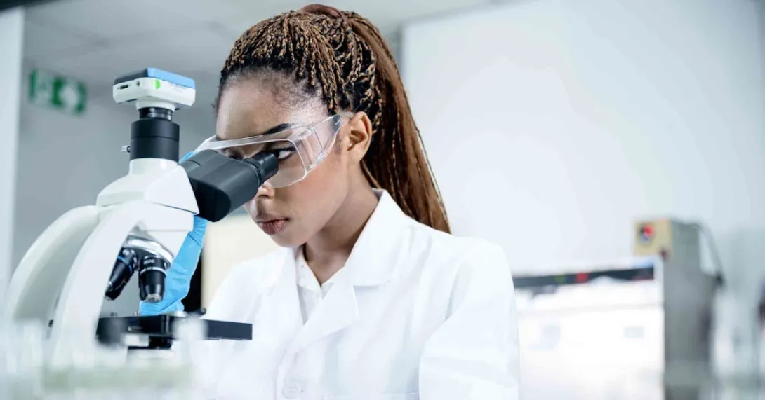 Scientist in a lab looking through a microscope