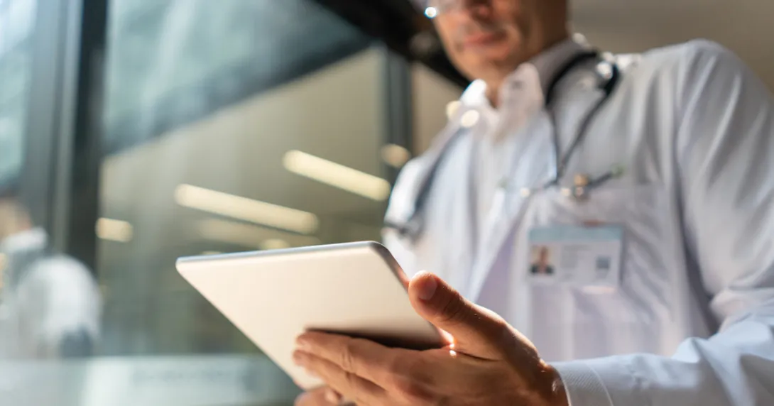 Healthcare provider standing up and looking at a tablet