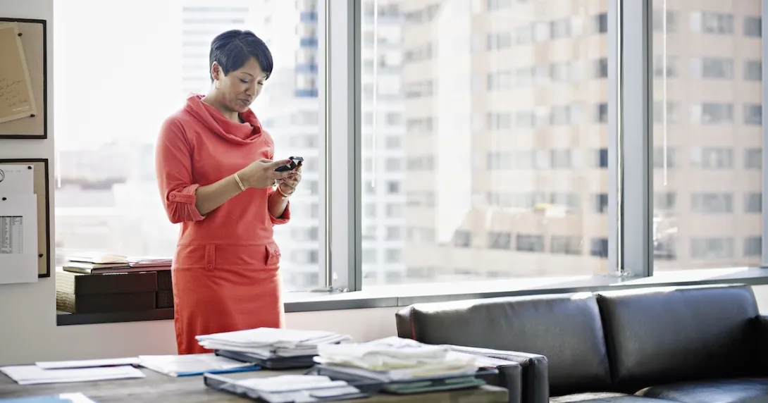 Person standing in an office and looking at their phone